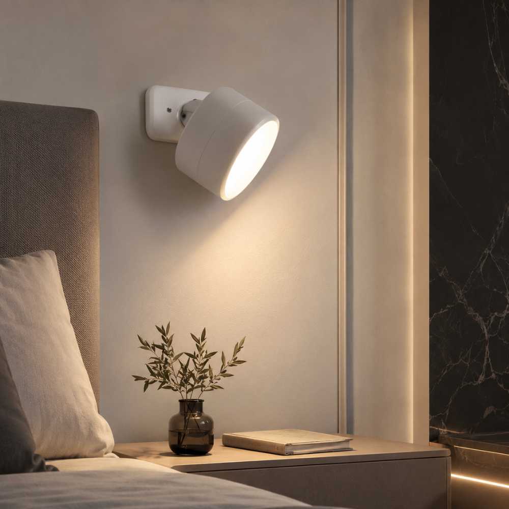 Applique murale LED blanche orientable installée près d’un lit