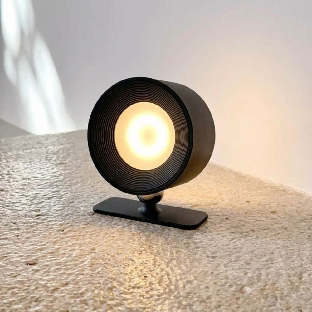 Applique murale LED orientable noire posée sur une surface avec lumière chaude
