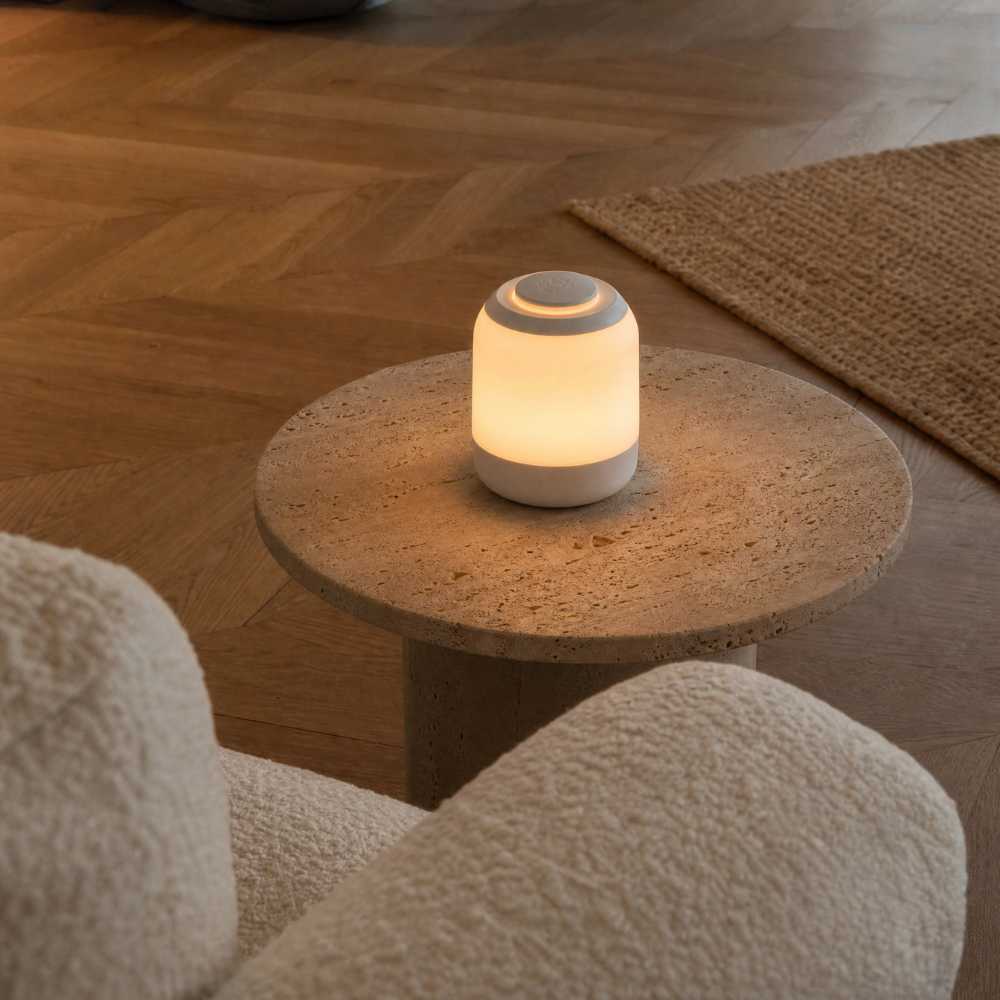 Lampe LED compacte sans fil diffusant une lumière chaude sur une table basse